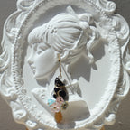 Hand holding a pair of earrings on a white ornate plate