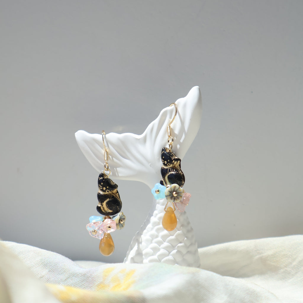 Earrings with colorful beads on a white shell against a gray background
