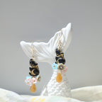 Beaded earrings with colorful beads on a white shell against a gray background