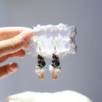Hand holding a pair of earrings on a white lace background