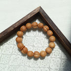 Wooden beaded bracelet on a textured surface with a wooden frame