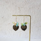 Pair of decorative earrings on a gold stand against a light background