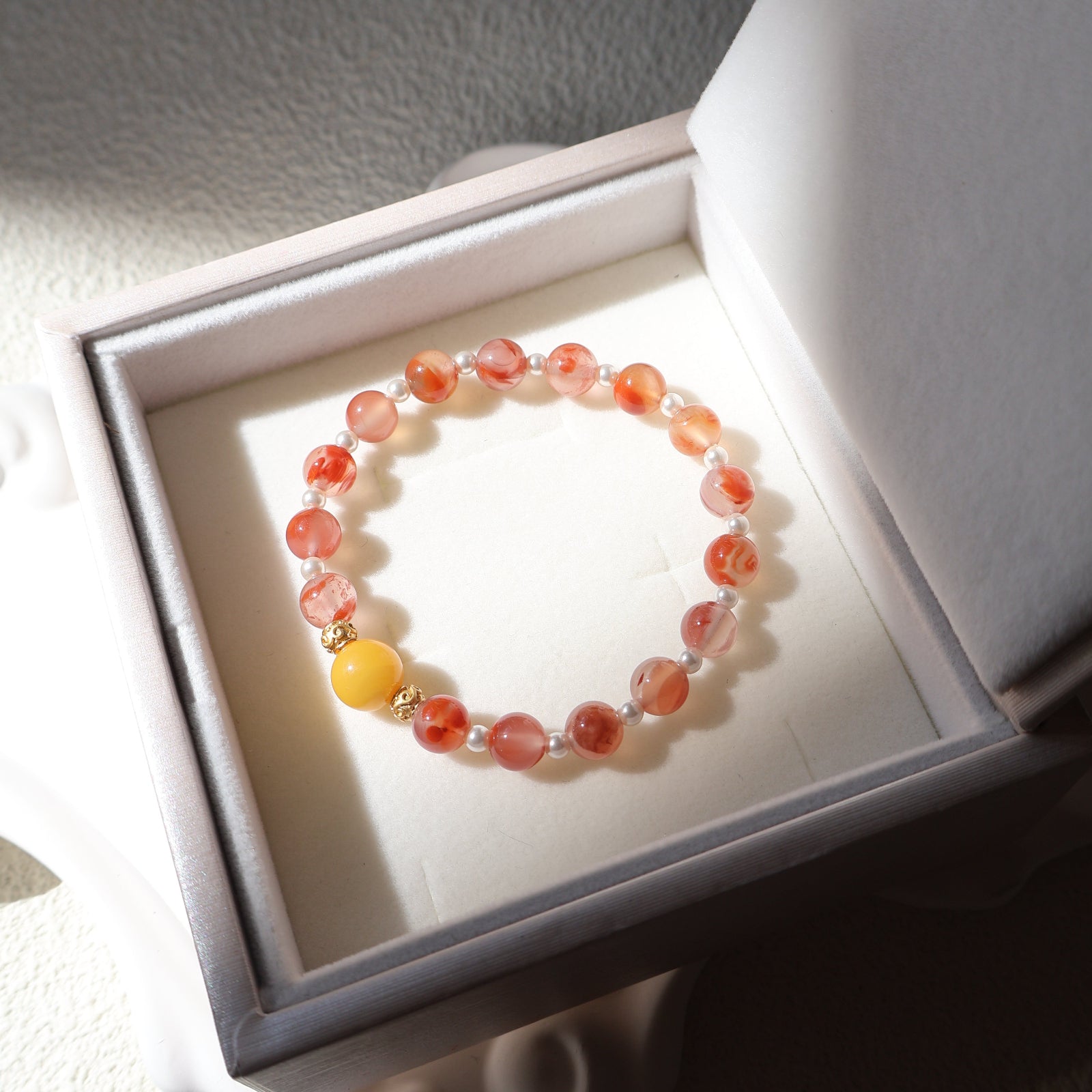 Beaded bracelet with orange and yellow beads in a white jewelry box