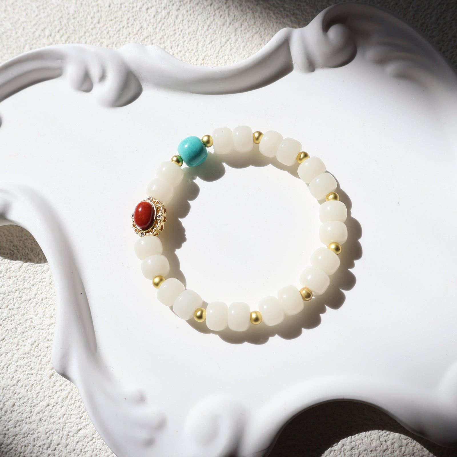 Bracelet with white beads and colored stones on a decorative white holder