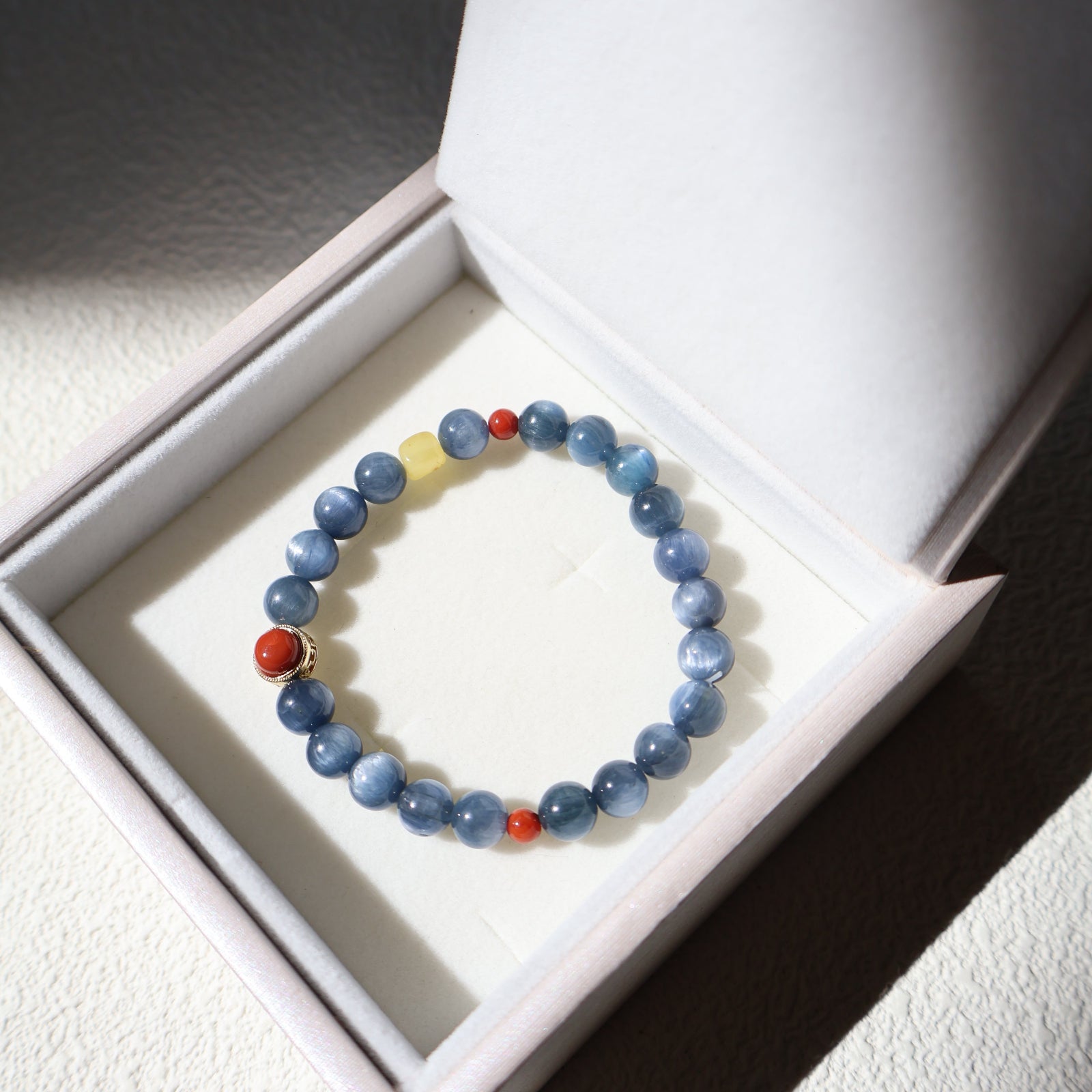 Blue beaded bracelet with red and yellow accents on a white box