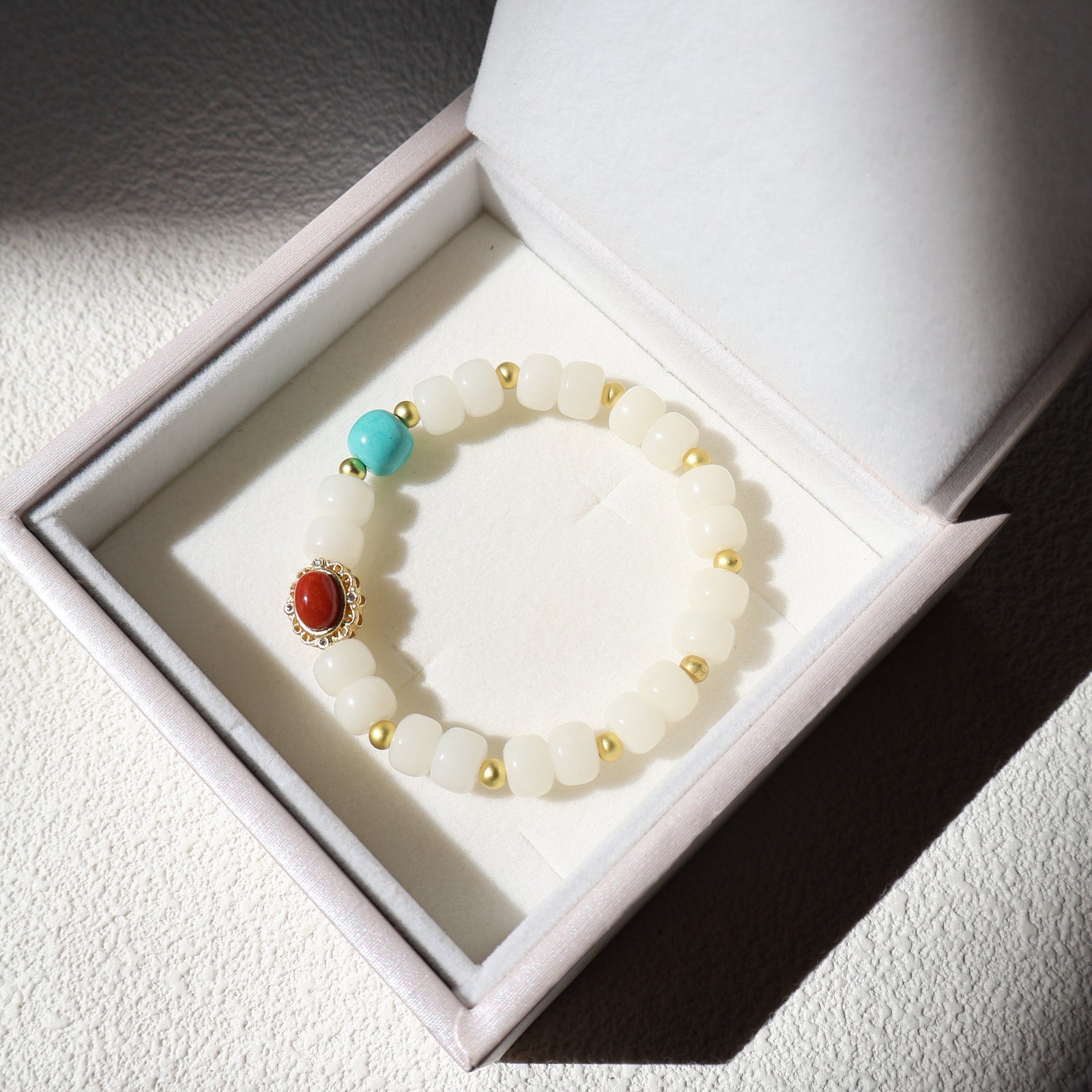 White beaded bracelet with colored stones in a white box