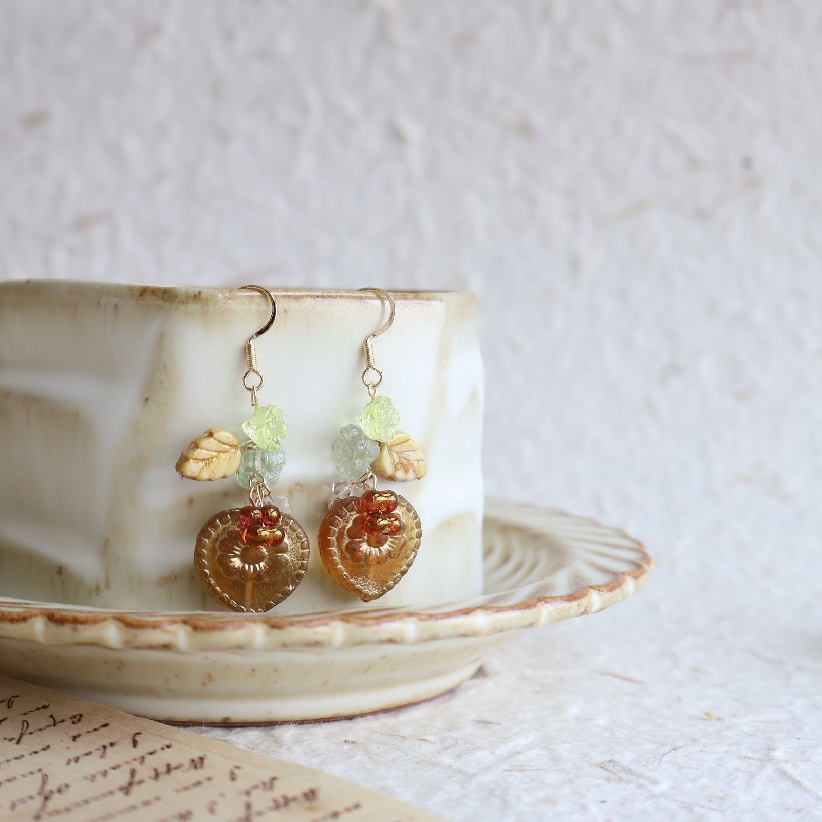 Pair of earrings with colorful stones displayed on a shell