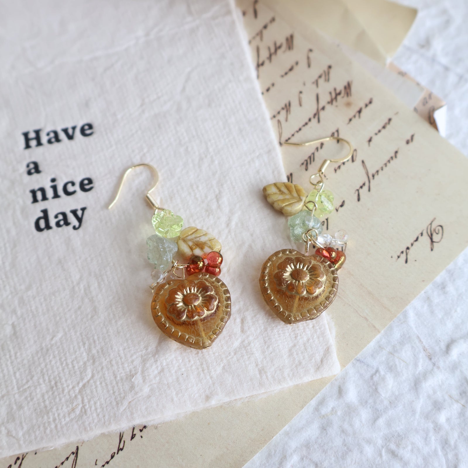 Pair of gold floral earrings on a textured paper background