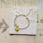Gold bracelet with green beads on a textured card with vintage design