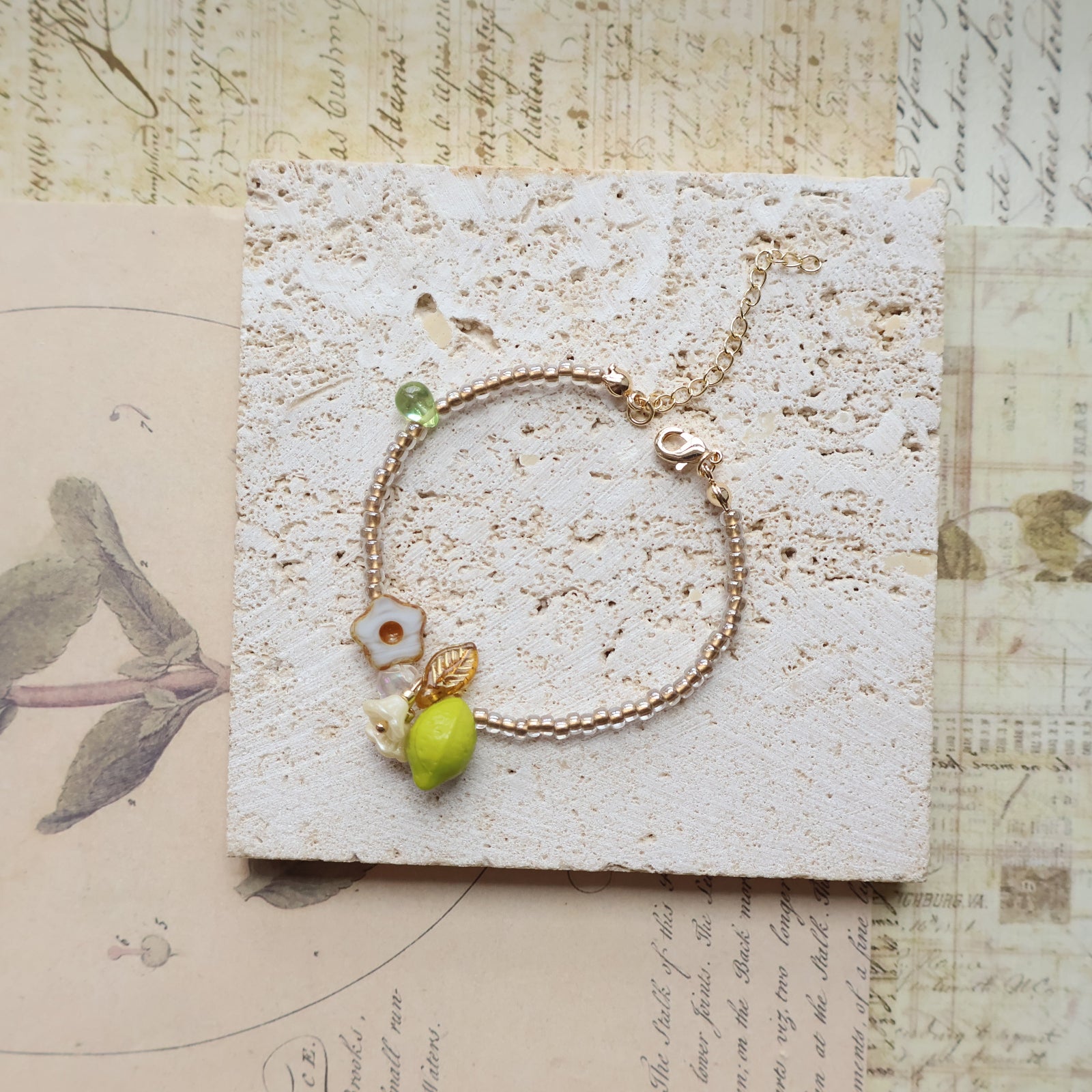 Gold bracelet with green beads on a textured card with vintage design