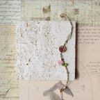 Bracelet with colorful beads on a textured card with vintage text and illustrations