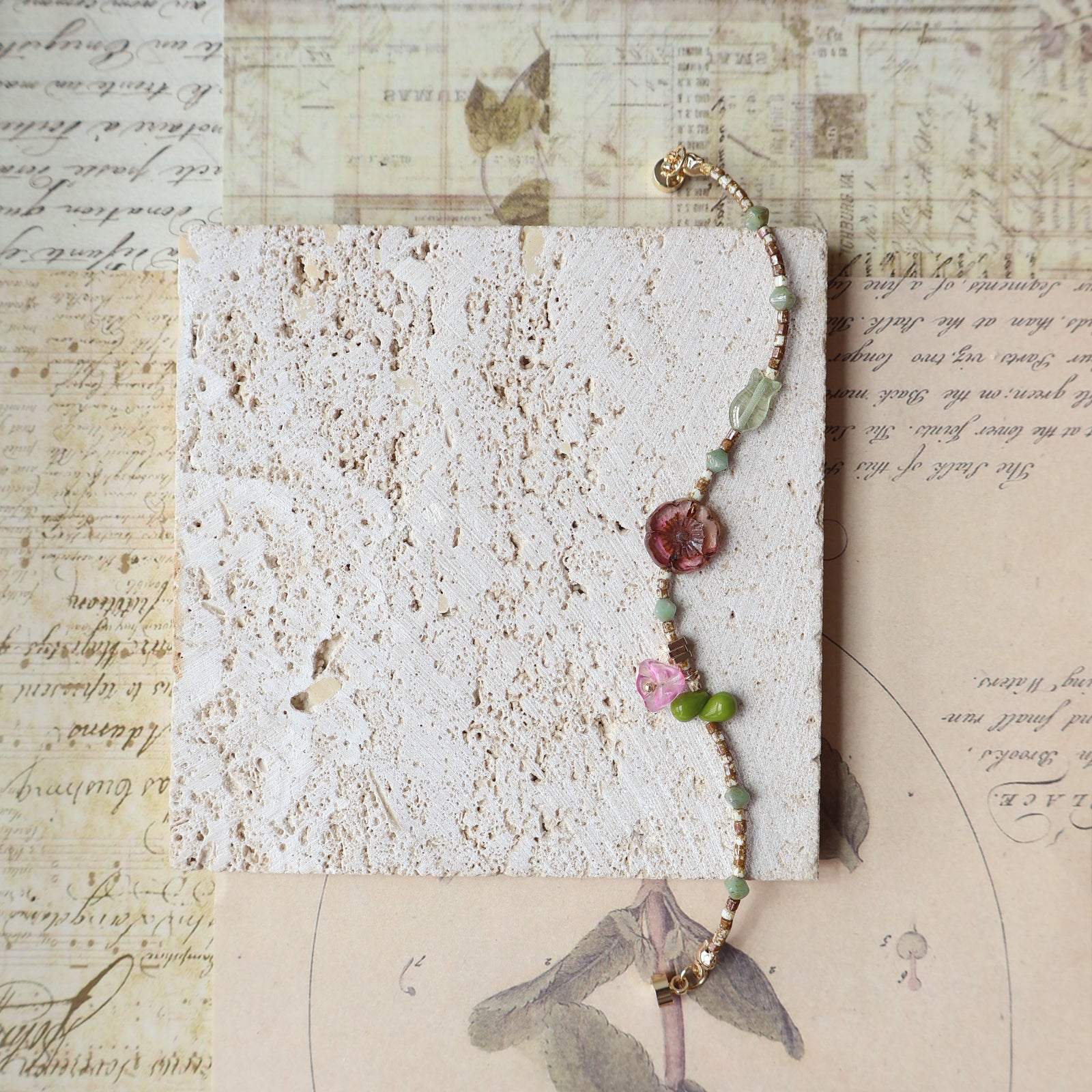 Bracelet with colorful beads on a textured card with vintage text and illustrations