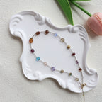Multicolored beaded necklace on a white decorative plate with a light background