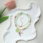Two beaded bracelets on a decorative white dish with a pink tulip in the background.