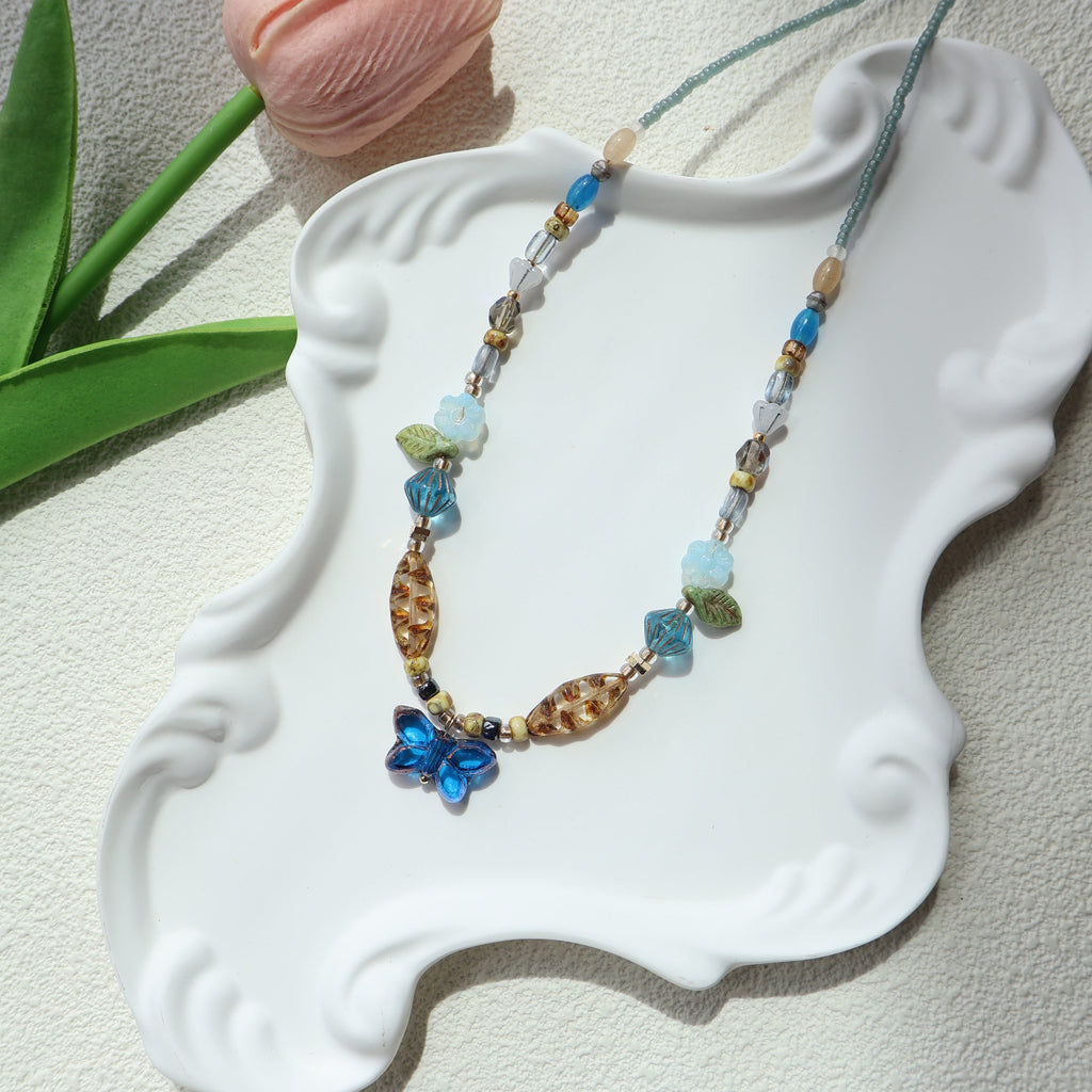 Beaded necklace with butterfly pendant on a decorative white stand