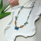 Beaded necklace with butterfly pendant on a decorative white stand