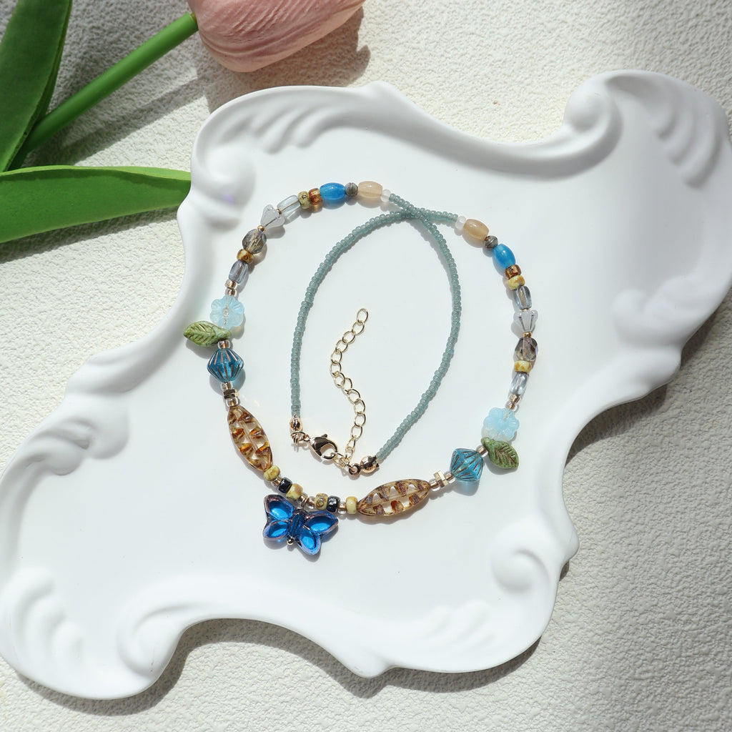 Two beaded necklaces on a decorative white stand with a light background