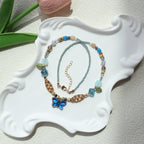 Two beaded necklaces on a decorative white stand with a light background