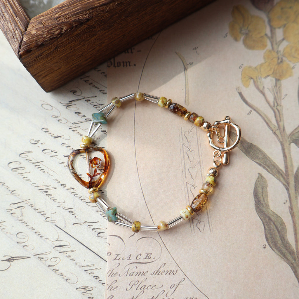 Bracelet with heart clasp on an old letter with floral illustrations