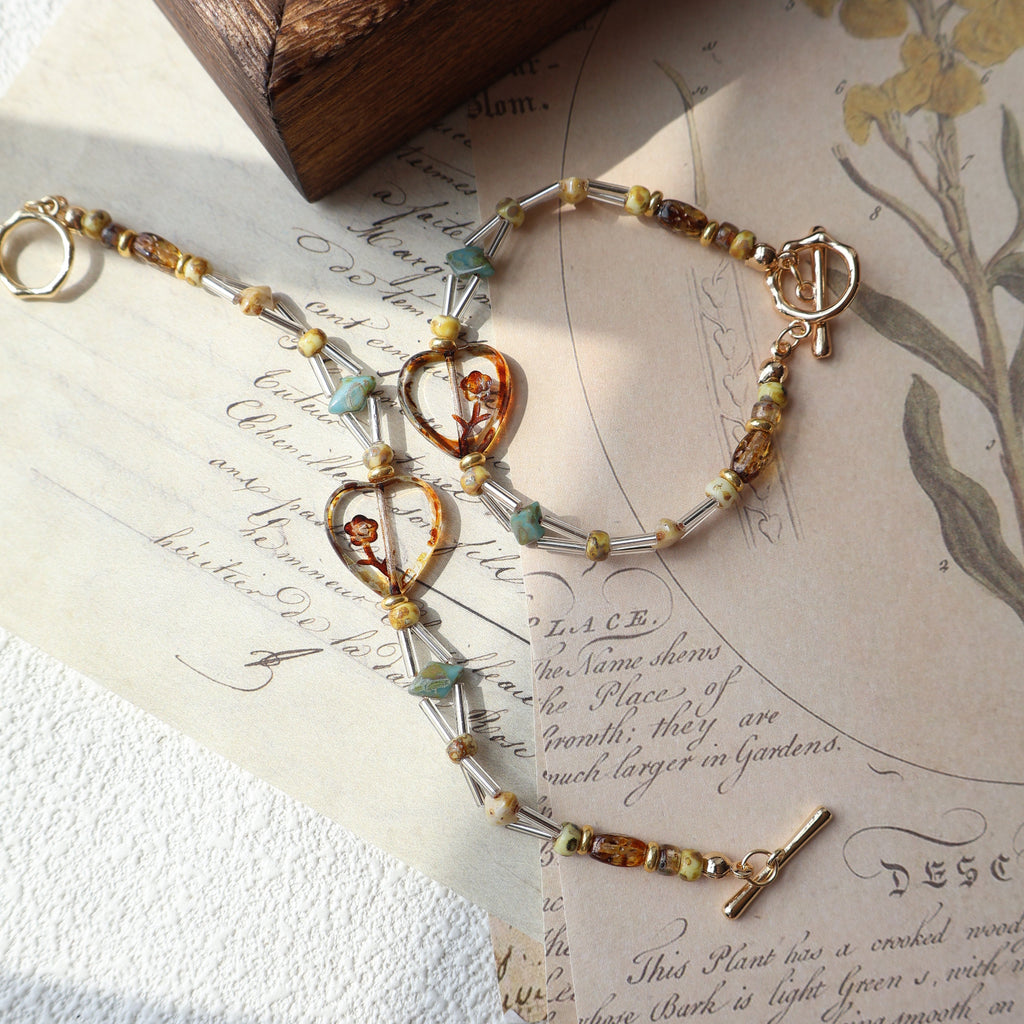 Bracelet with gold and silver beads on an old letter with floral illustrations