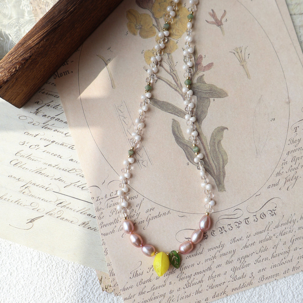 Pearl necklace with yellow and green accents on an old letter with floral illustrations