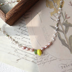 Pearl necklace with a yellow pendant on an old letter with floral illustrations