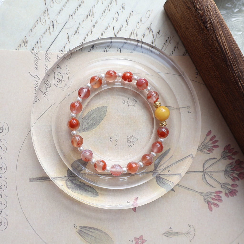 Bracelet with red and yellow beads on a decorative plate with floral patterns