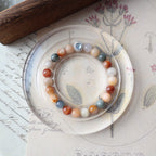 Decorative plate with a bracelet on a surface with writing and a wooden object.