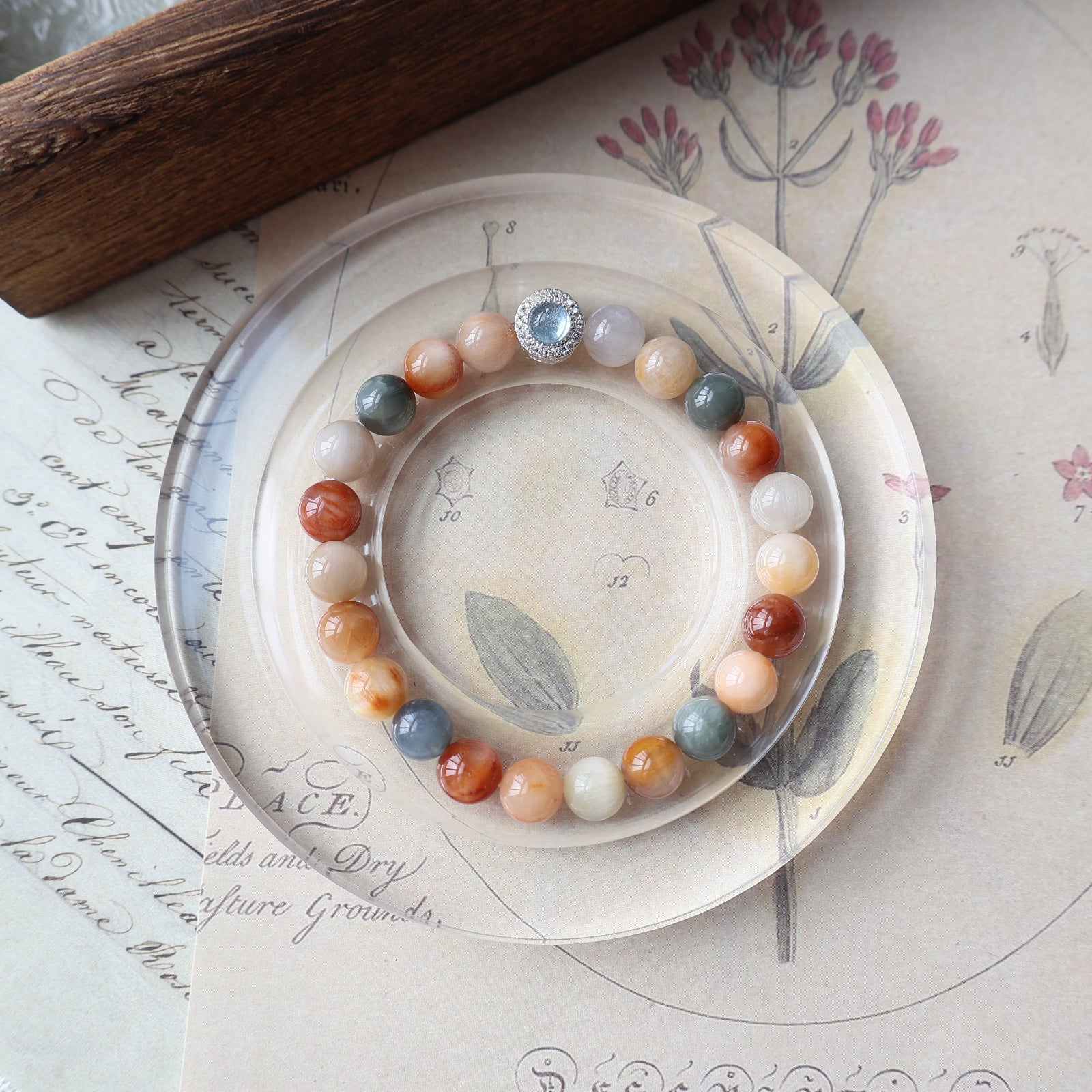 Decorative plate with a bracelet on a surface with writing and a wooden object.