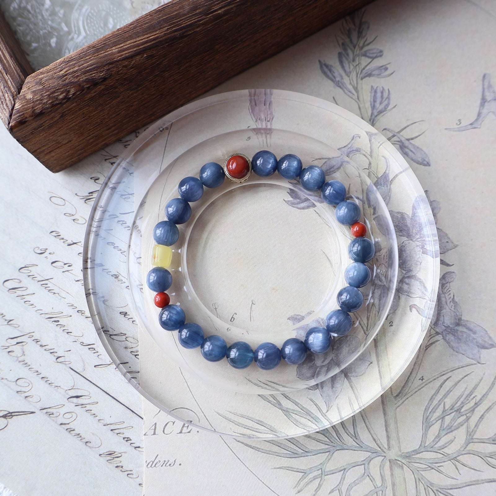 Blue beaded bracelet with red accents on a decorative plate with floral patterns