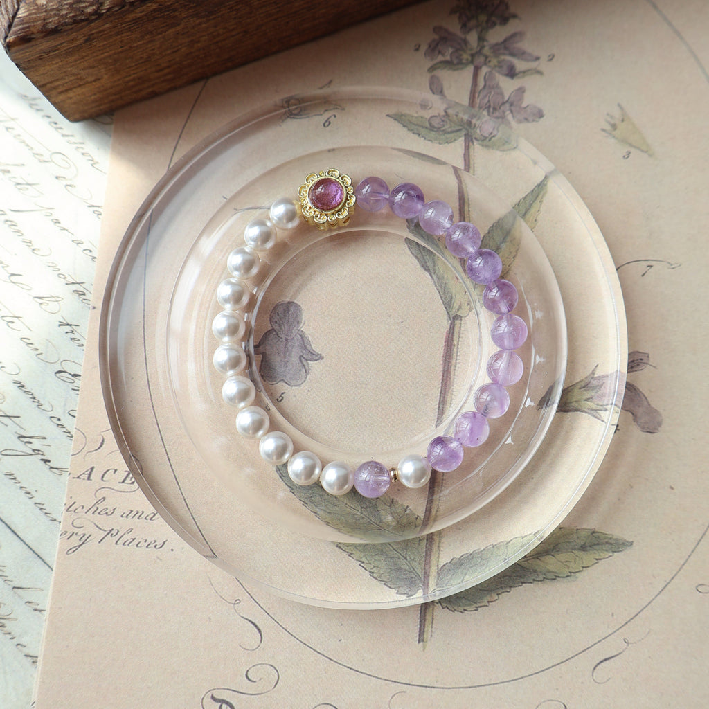 Pearl and purple beaded bracelet on a decorative plate with floral designs