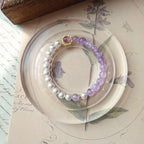 Pearl and purple beaded bracelet on a decorative plate with floral designs