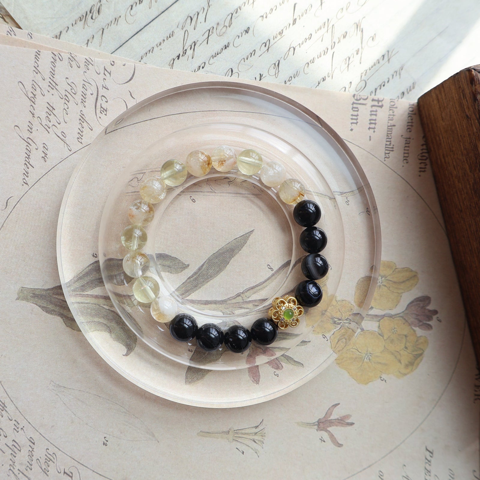 Bracelet with black and clear beads on a decorative plate with floral design