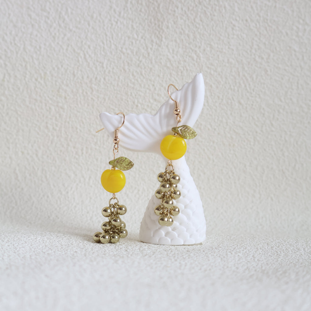 Decorative hair clip with white bow, gold beads, and yellow centers on a textured white background