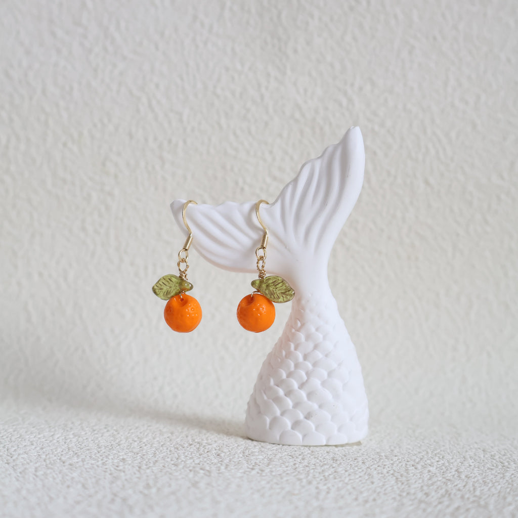 White whale tail with orange and green beads on a textured white background