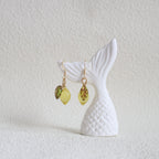 Mermaid tail and earrings on a textured white surface