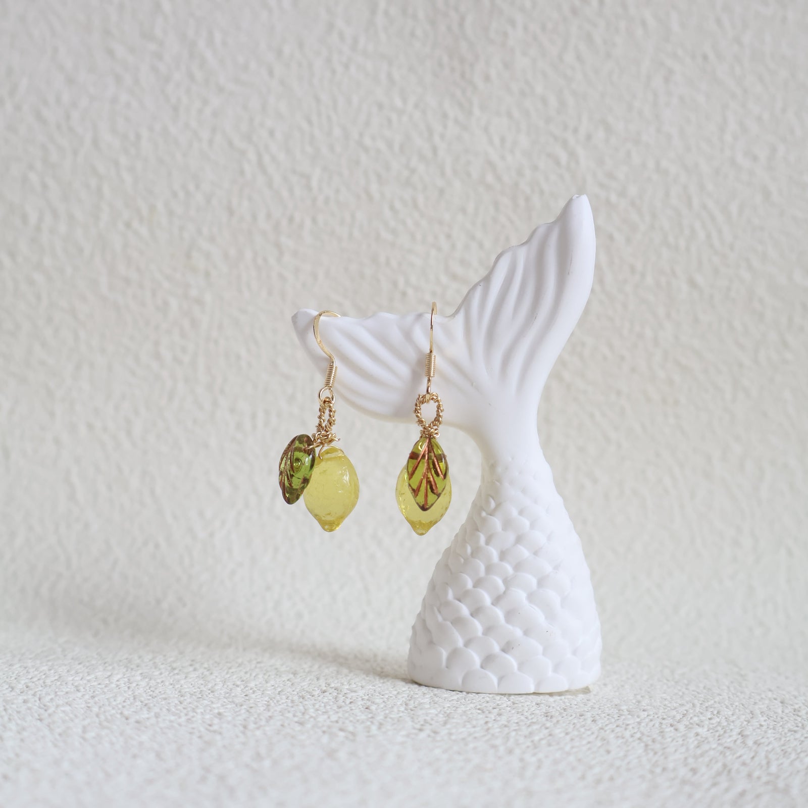 Mermaid tail and earrings on a textured white surface