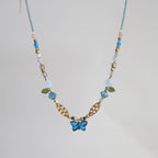 Beaded necklace with a blue flower pendant on a light gray background