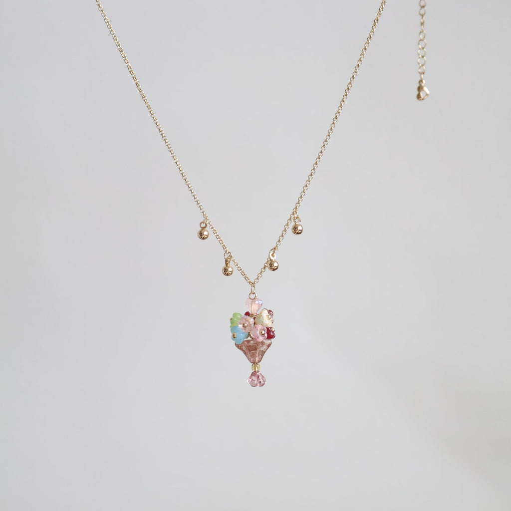 Gold necklace with a floral pendant on a light gray background