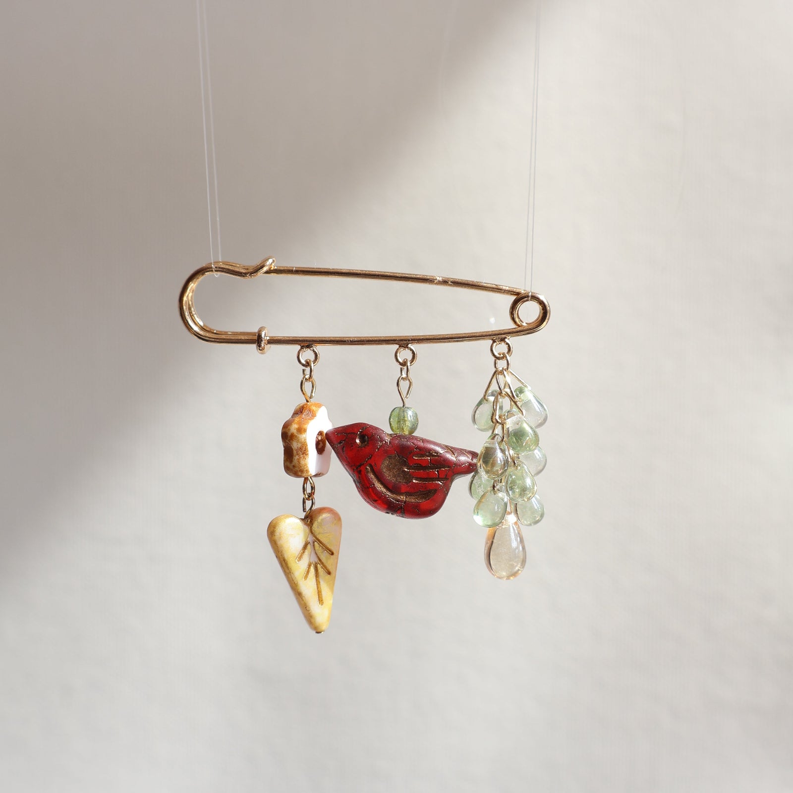 Decorative brooch with red central element and gold accents on a white background