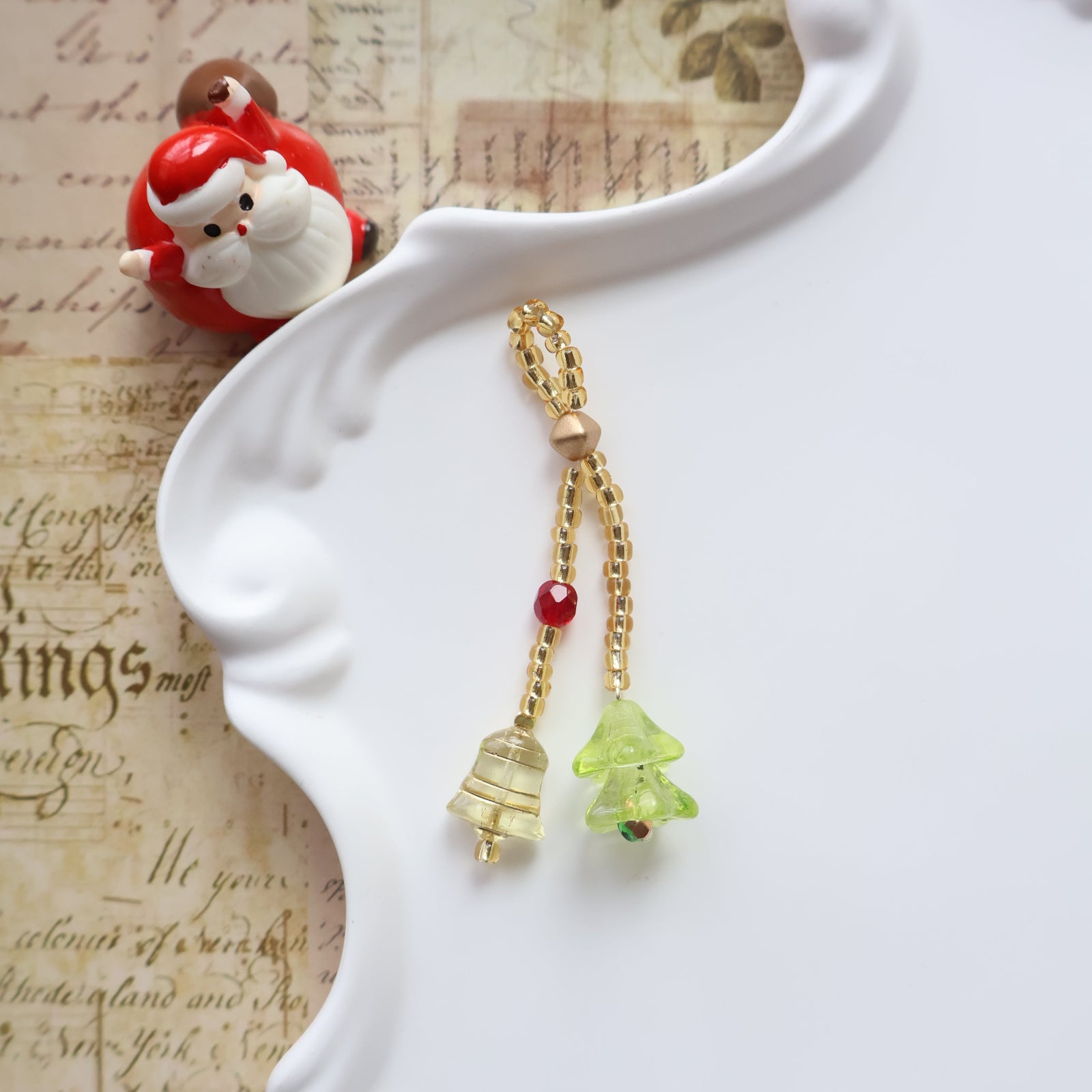 Decorative keychain with gold chain, green star, and red beads on a white dish with a vintage background.
