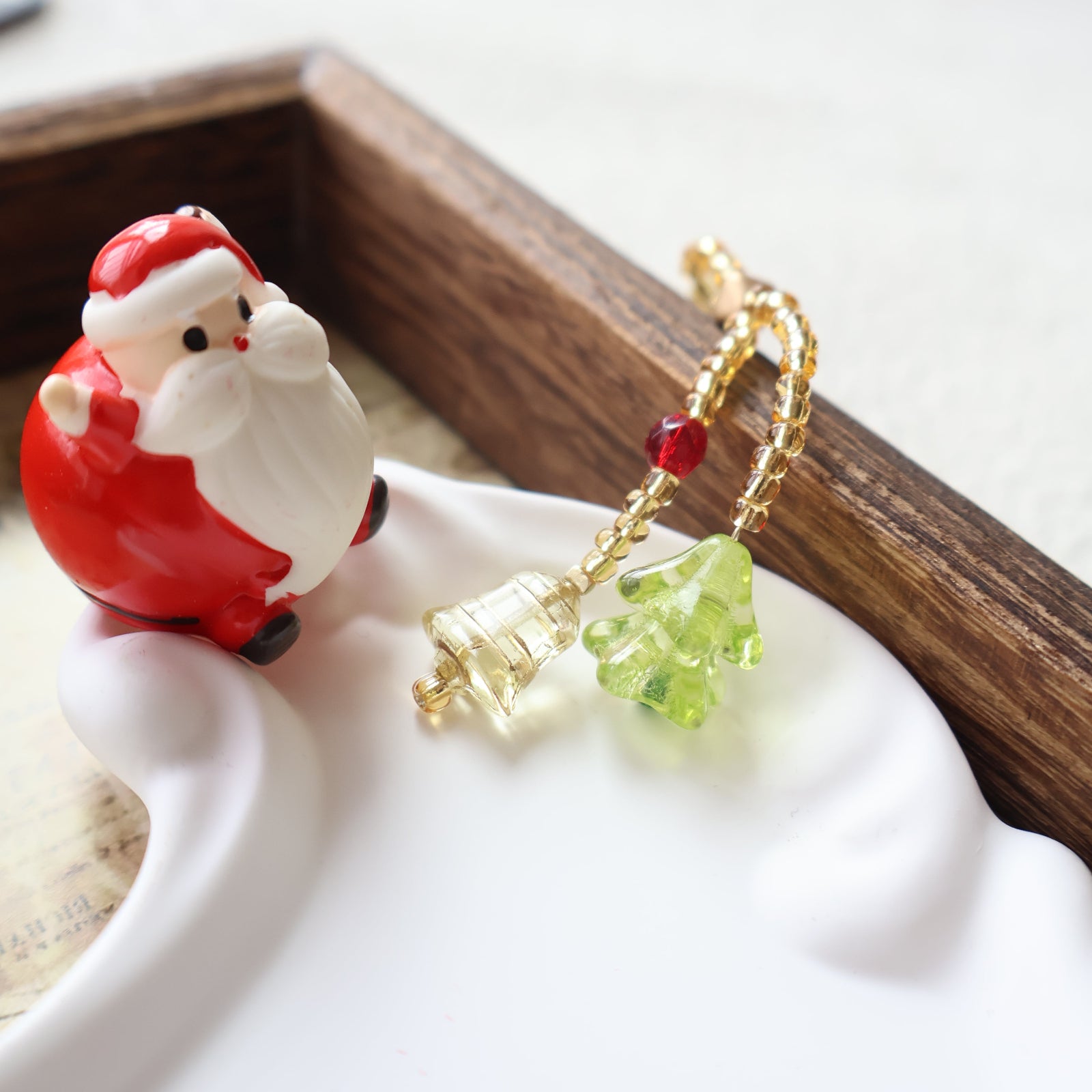 Decorative keychain with Santa Claus figure and Christmas tree charm on a wooden surface.