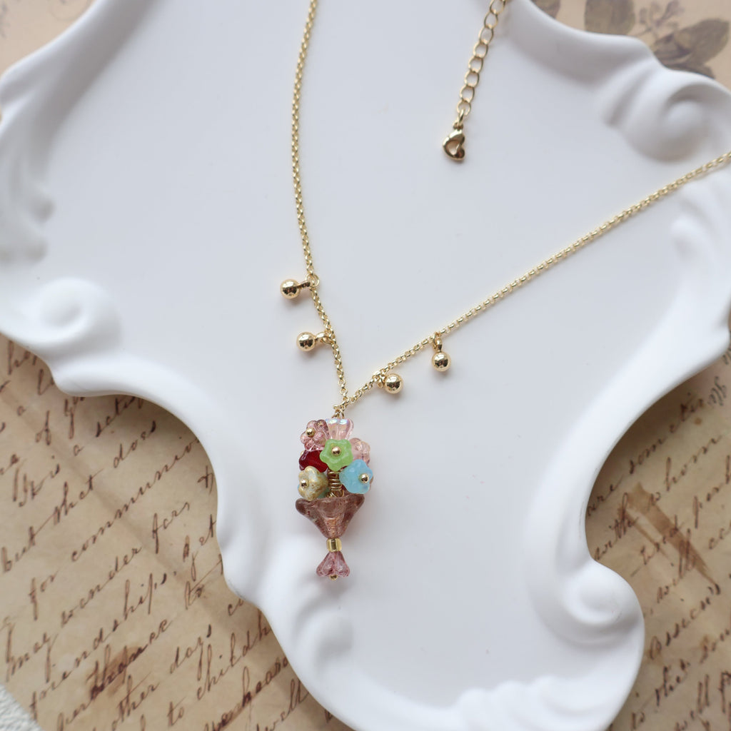 Gold necklace with colorful beads on a white jewelry stand.