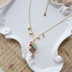 Gold necklace with colorful beads on a white jewelry stand.