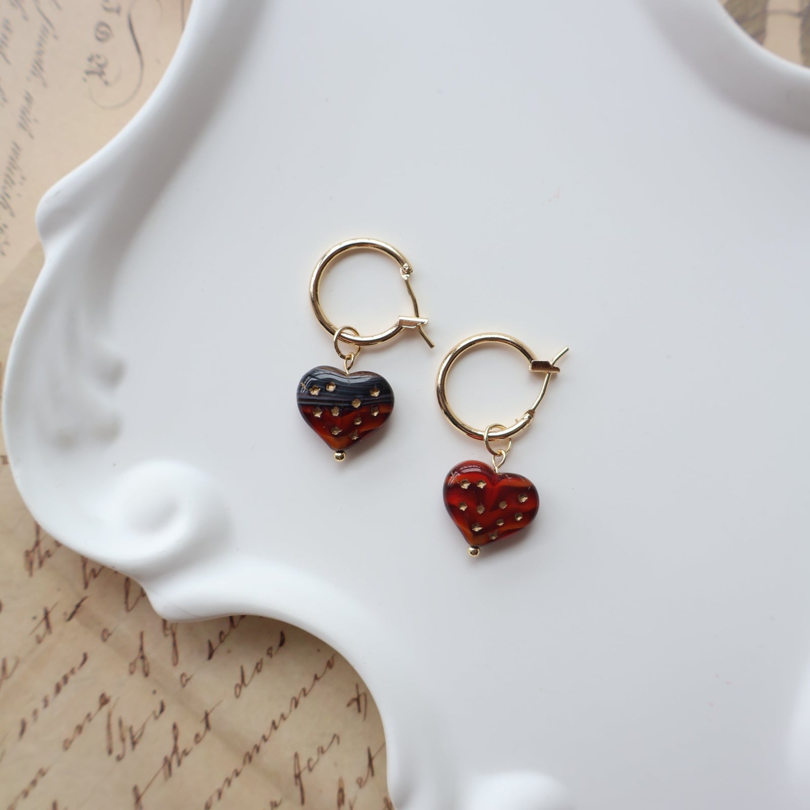 Two pairs of earrings on a white dish with a textured background