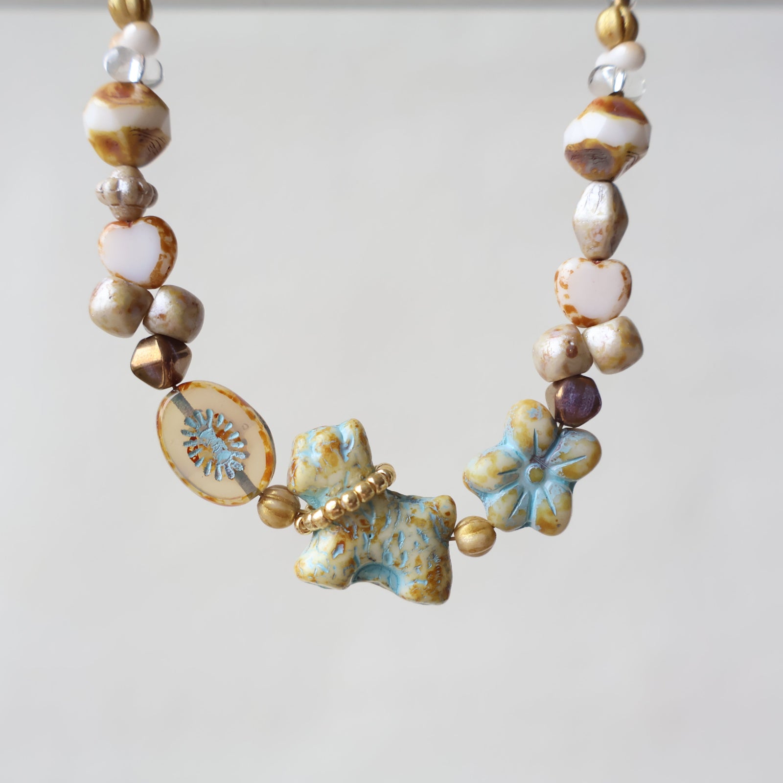 Necklace with ceramic beads and floral elements on a light background