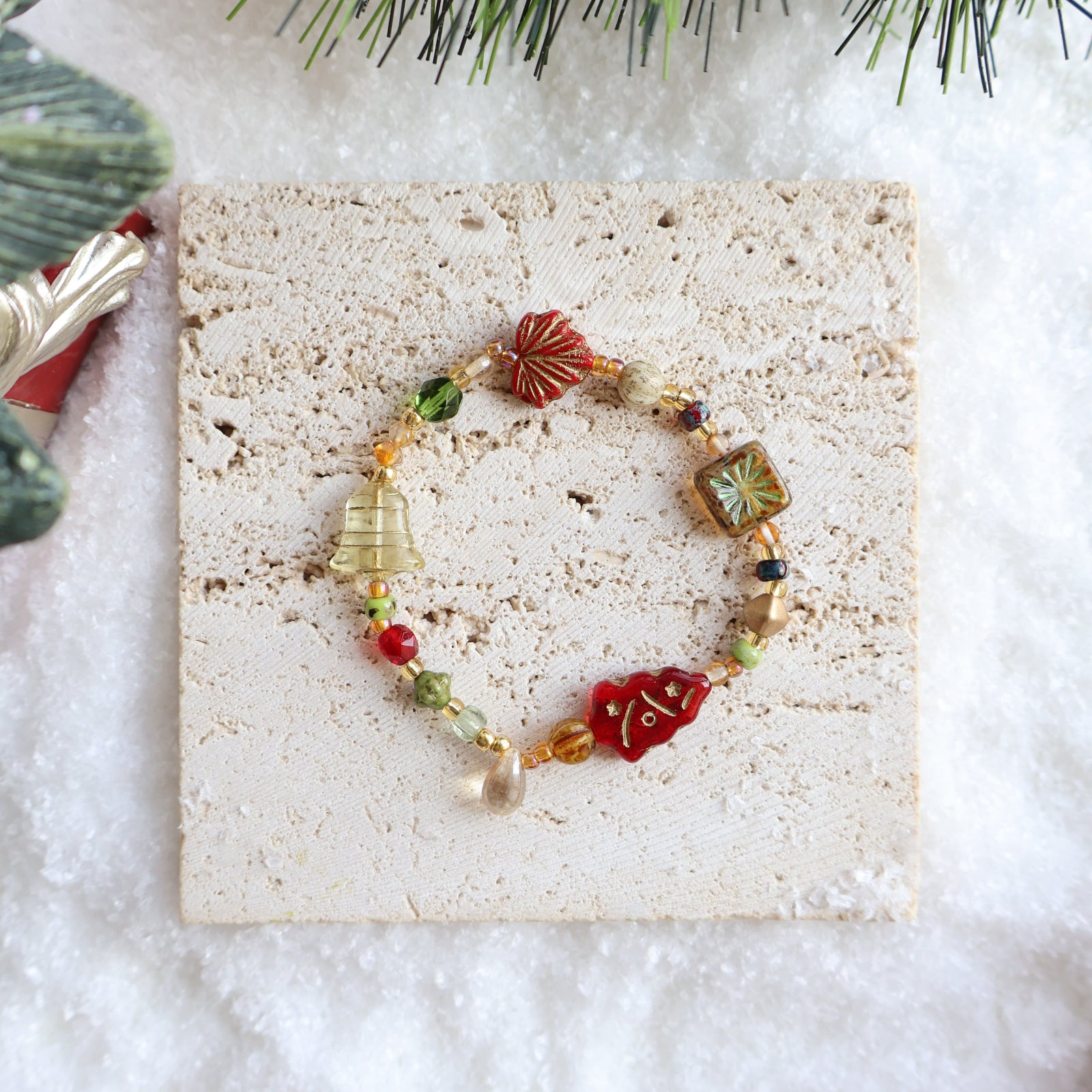 Colorful beaded bracelet on a textured stone surface with Christmas decorations.