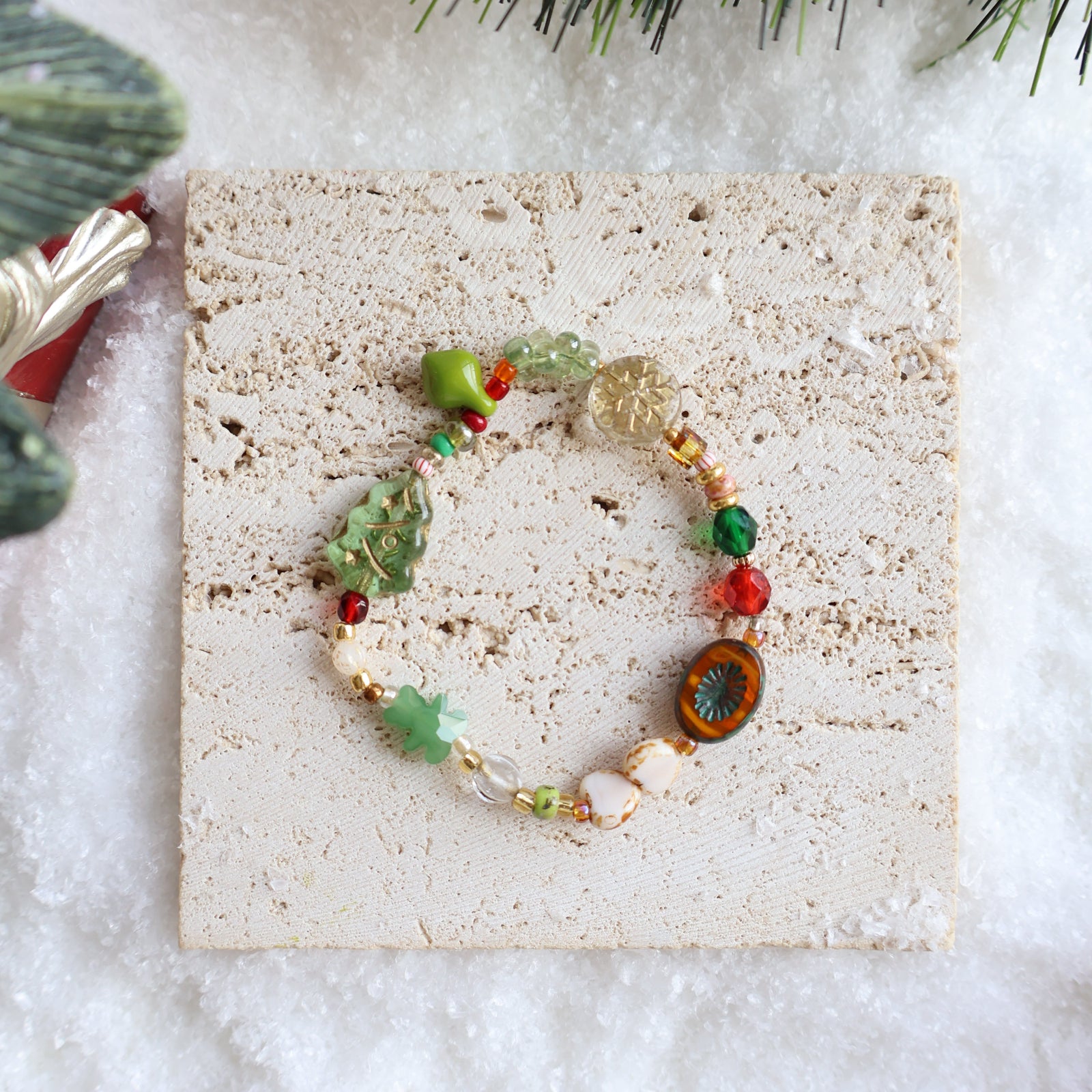 Colorful beaded bracelet on a textured stone surface with greenery in the background