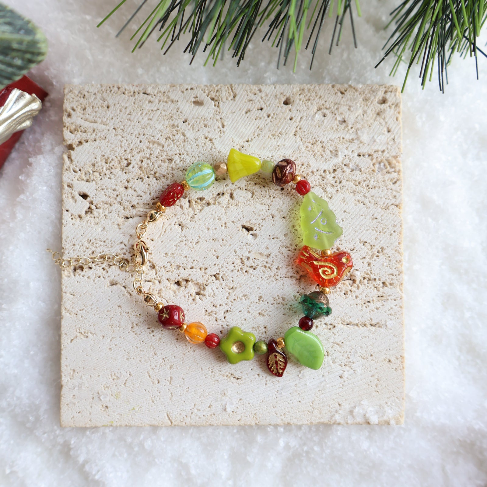 Colorful beaded bracelet on a textured beige surface with Christmas decorations.