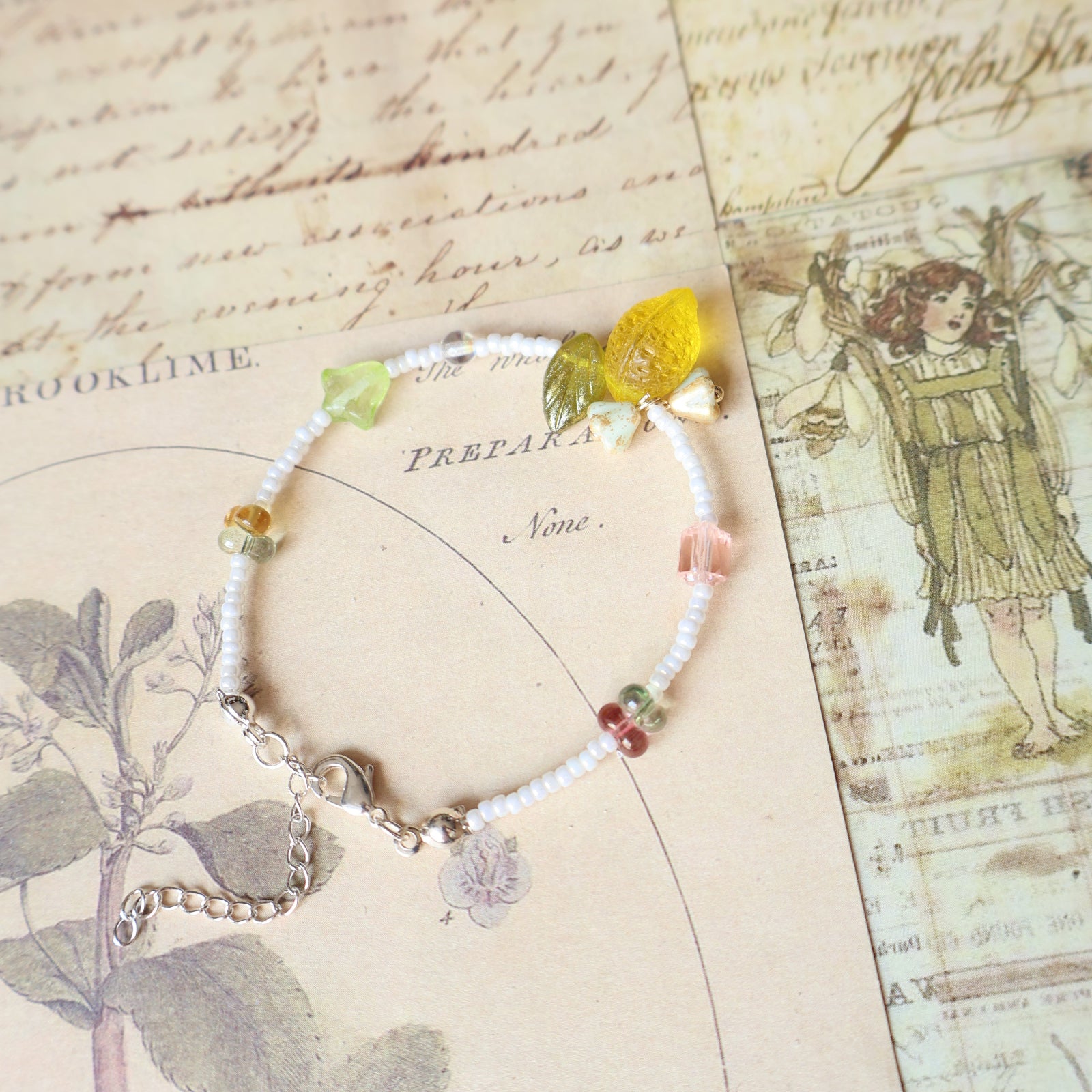 Bracelet with colorful beads and a yellow strawberry charm on an old map background
